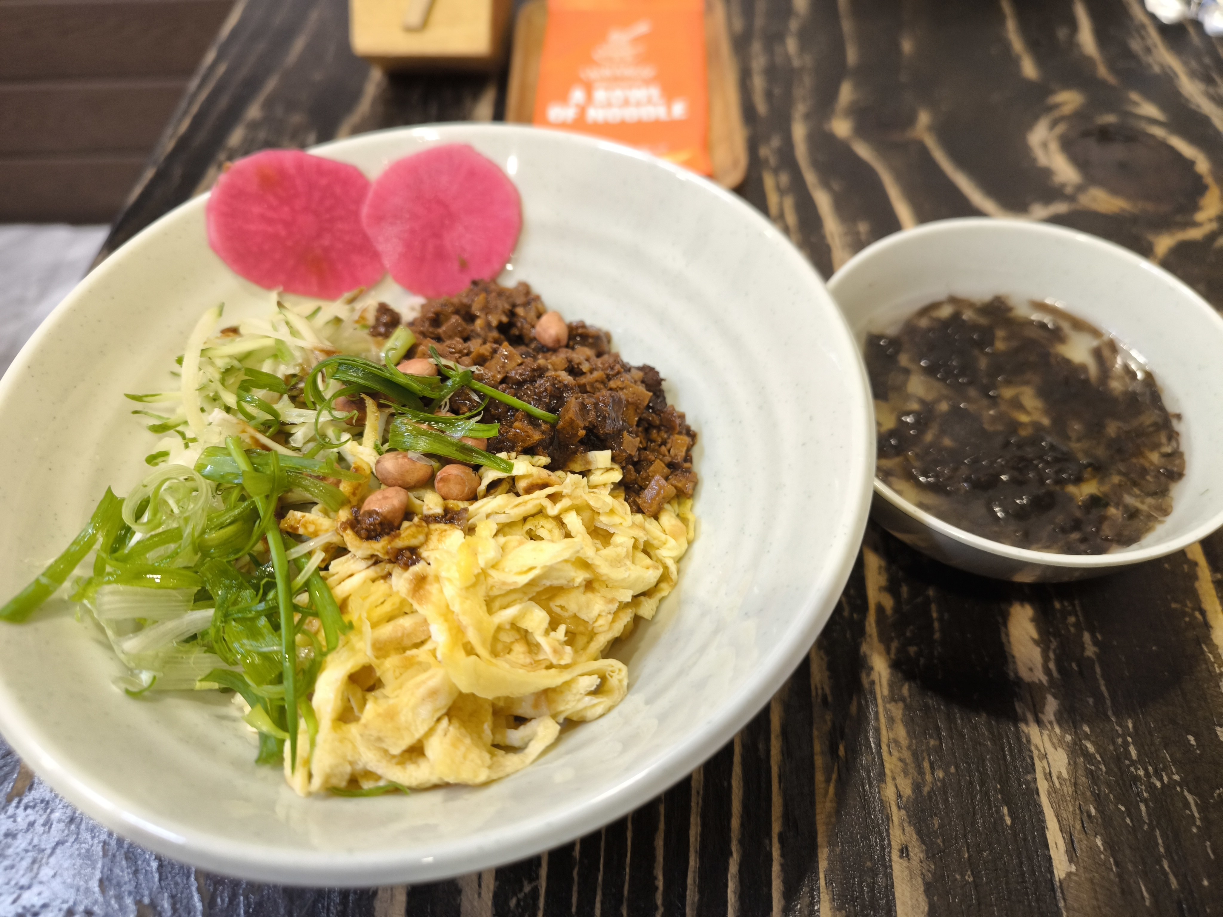 A bowl of mixed noodles with egg ribbons and greens
