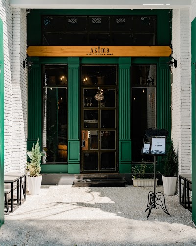 AKOMA Café & Fusion — mặt tiền: cửa gỗ xanh, gạch trắng, bảng vàng