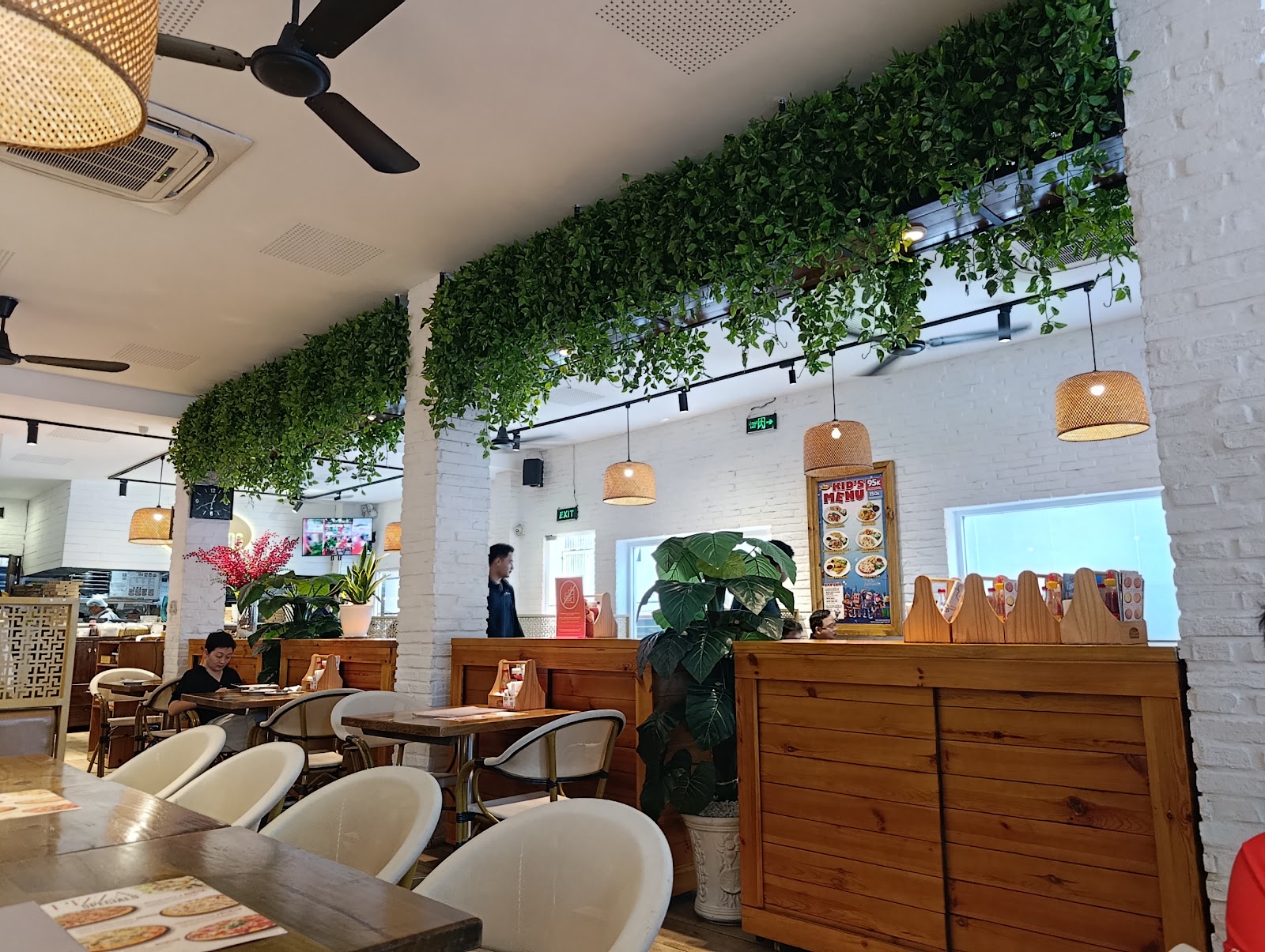 The dining area with the hanging green wall and rattan lamps