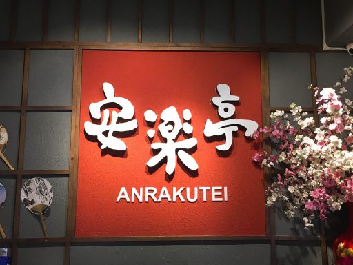 Bức tường đỏ mang chữ 安楽亭 trắng trong nội thất Anrakutei