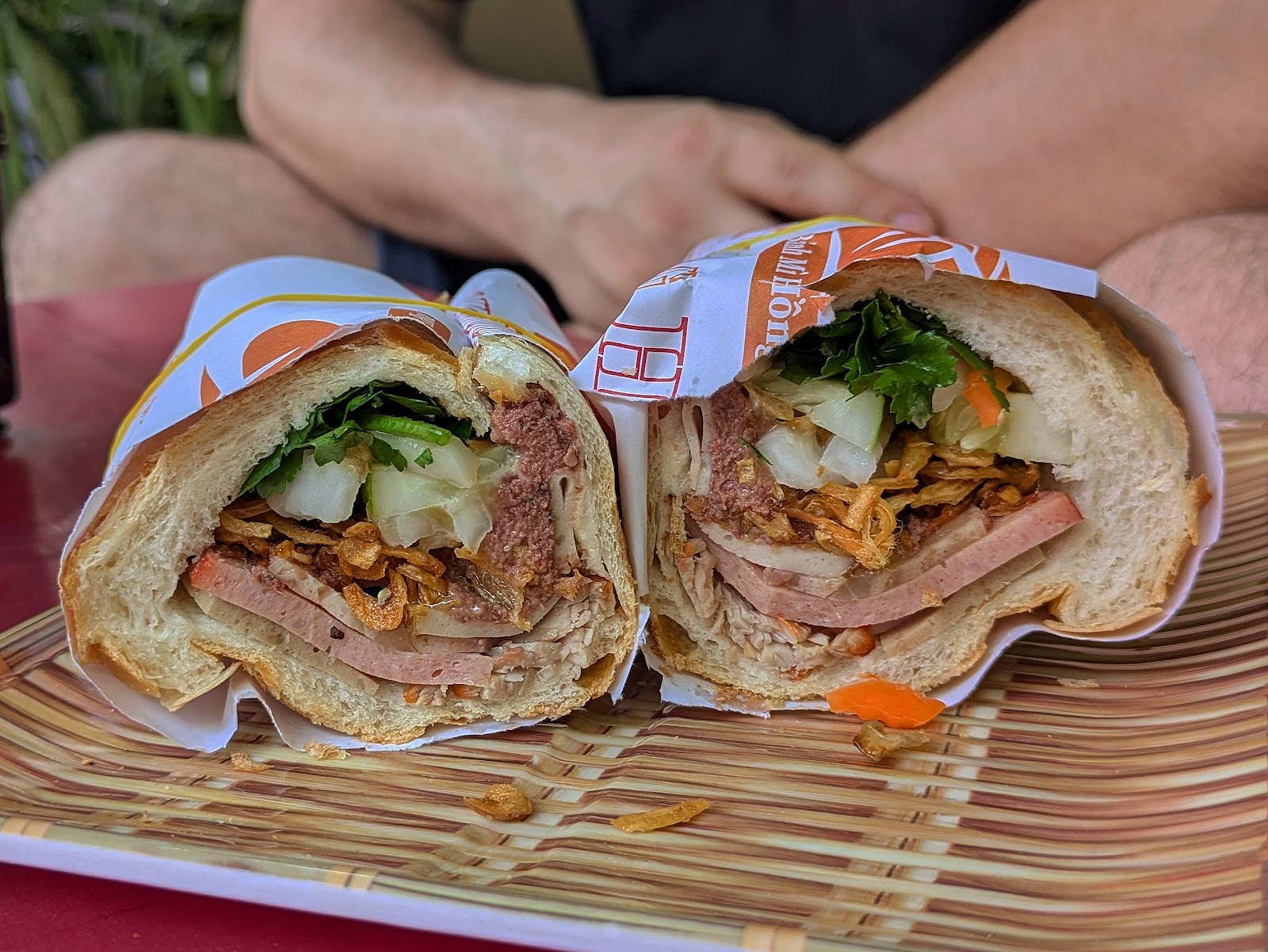 Mixed bánh mì cross-section — sausage, pâté, fried shallots, herbs