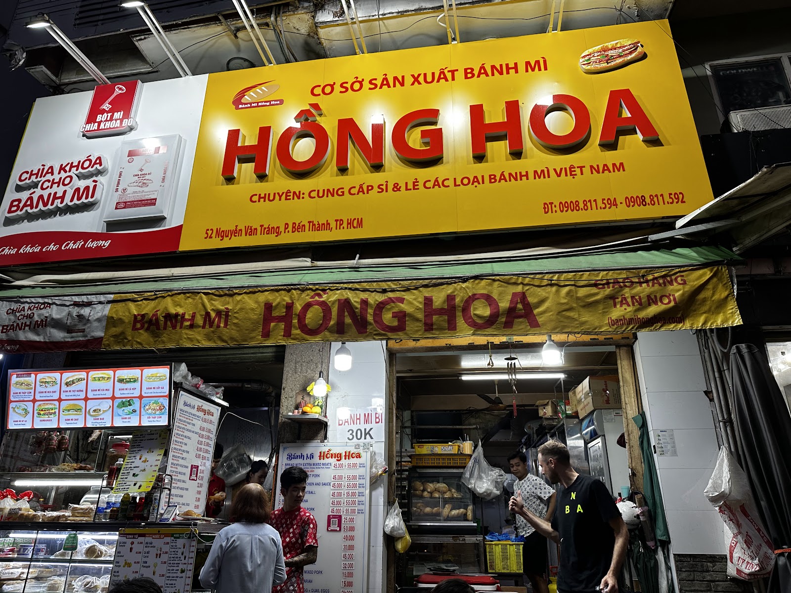 The yellow HỒNG HOA signboard lit at night