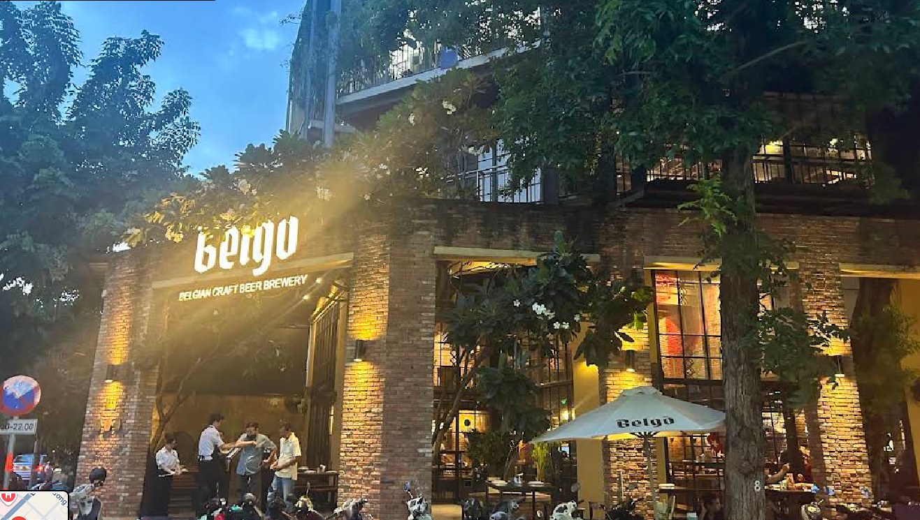 Mặt tiền Belgo lúc chạng vạng, cây xanh và bàn ngoài trời