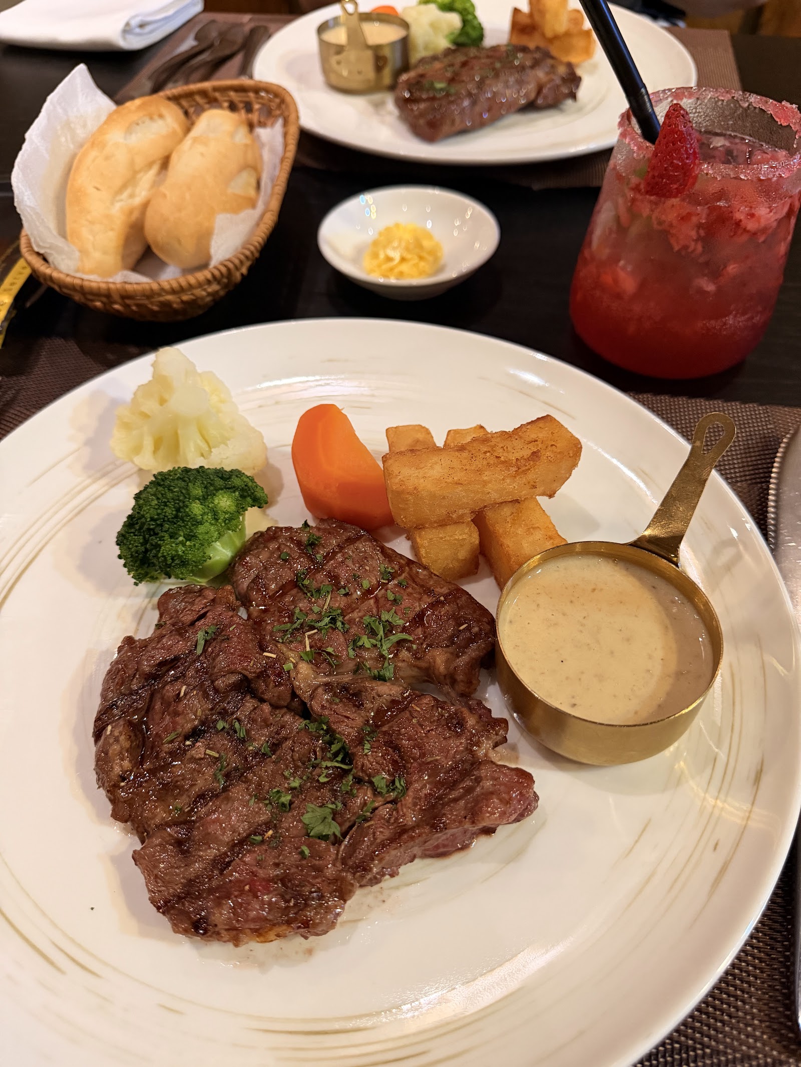 Ribeye steak in mushroom sauce with vegetables and a bread basket (diner photo by Tat Kha Di, Sep 2026)