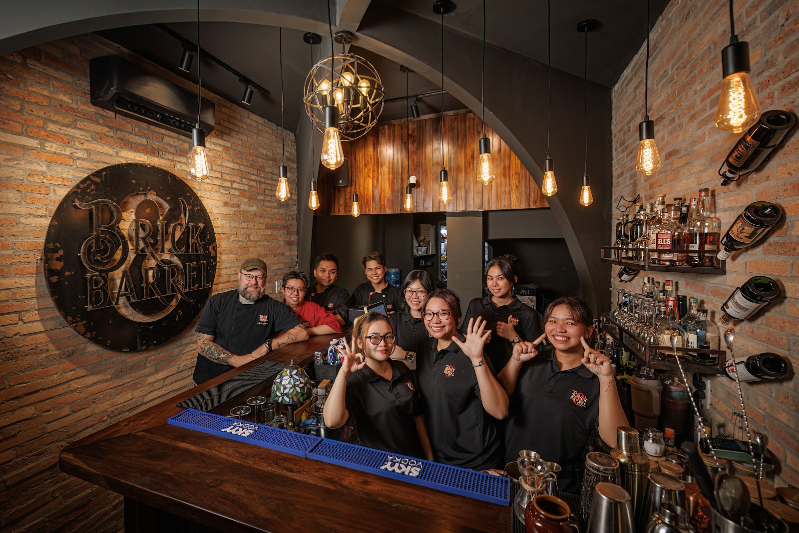 Không gian Brick & Barrel — bàn gỗ dài dưới ánh đèn ấm
