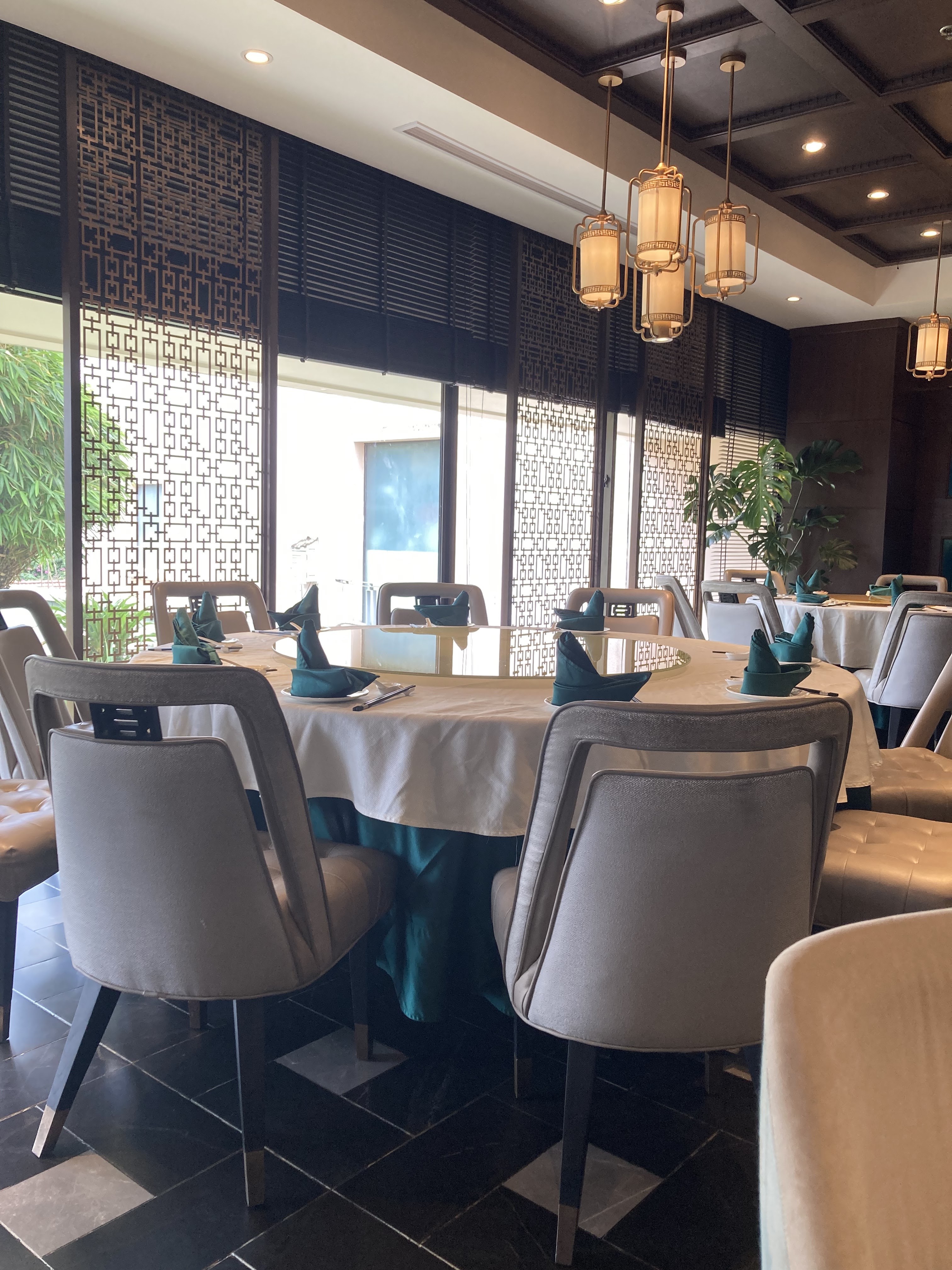 Bàn bên cửa sổ: vách lattice vàng, đèn lồng đồng, tre xanh ngoài hiên