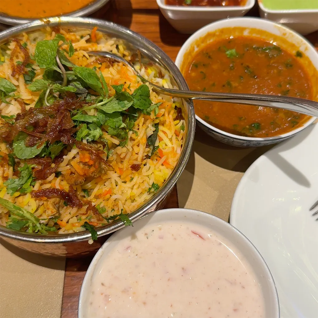 A clay pot of biryani with fried onion and mint