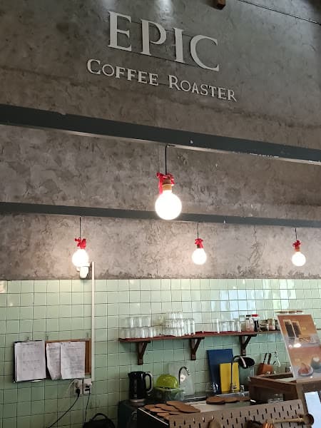 Chữ EPIC COFFEE ROASTER trên tường bê tông thô cạnh quầy bar