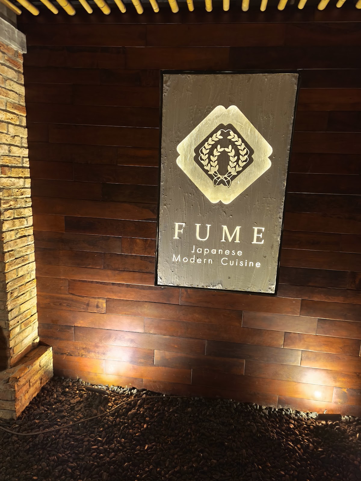 FUME 입구 — 월넛 벽 위 빛나는 다이아몬드 크레스트