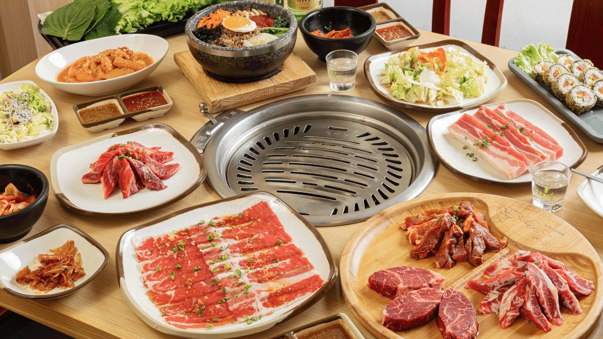 The full GoGi spread: tabletop grill, stone-pot bibimbap, tteokbokki, soju