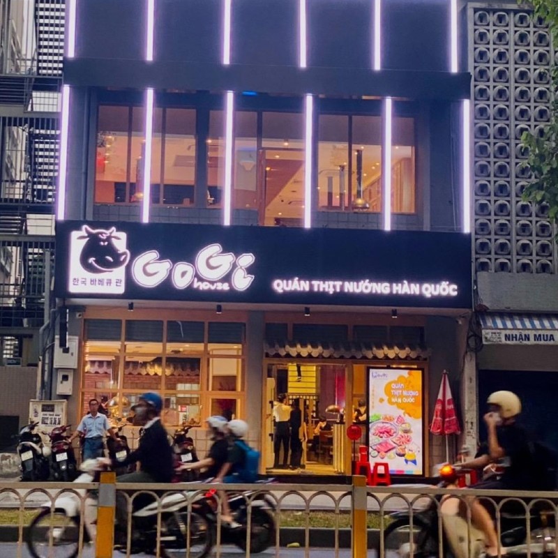GoGi House Tran Hung Dao storefront: black backlit sign, glass front, motorbikes on the boulevard
