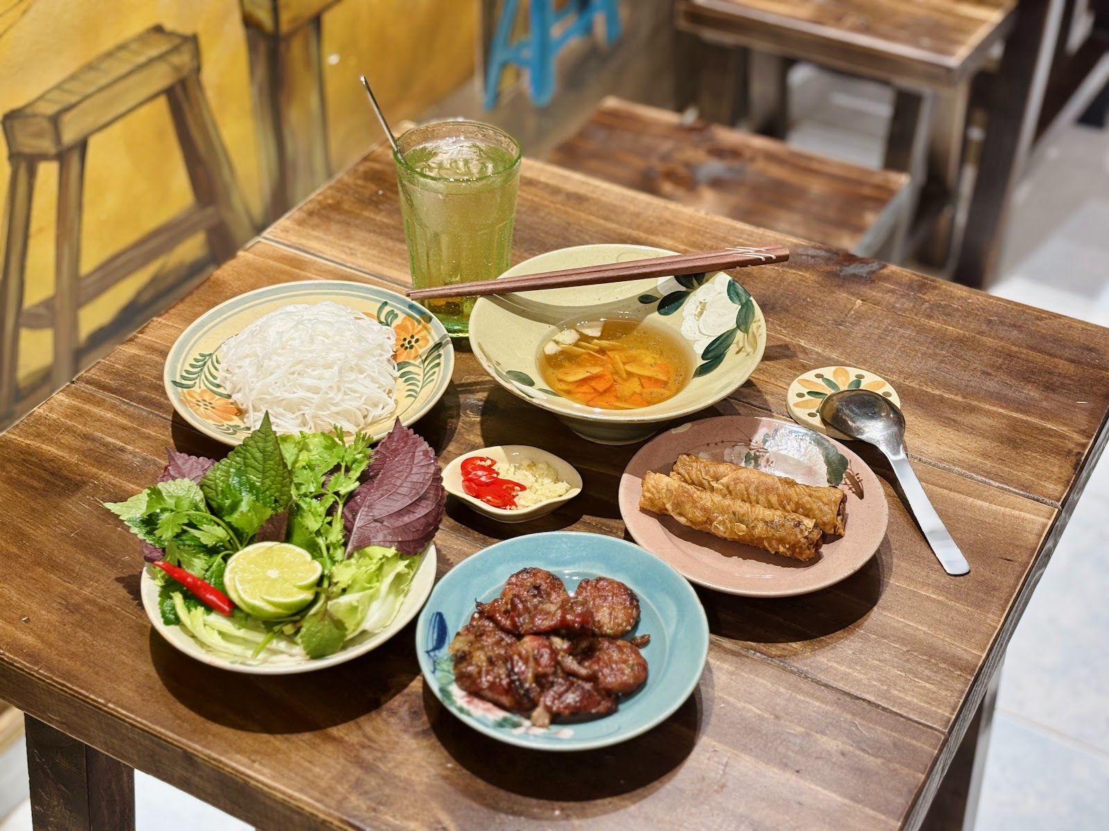 Mẹt bún chả đầy đủ: thịt nướng, bún, rau thơm, nem rán và ly nước