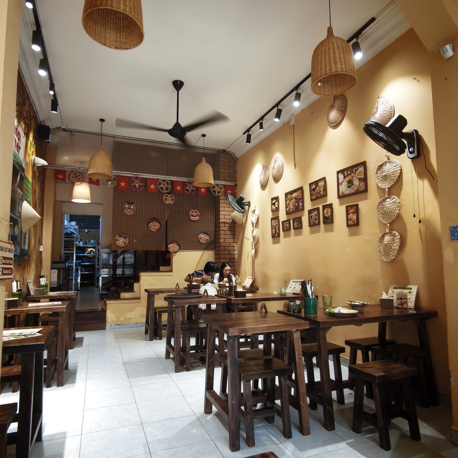 Tường treo ảnh món ăn, nón đan và mặt nạ tuồng trong quán