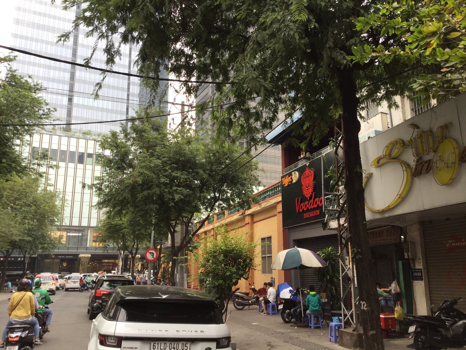 Ton That Thiep street outside the venue — trees, towers, blue stools out front