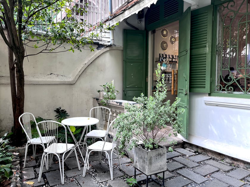 The courtyard: deep-green shutters, white bistro set under the trees