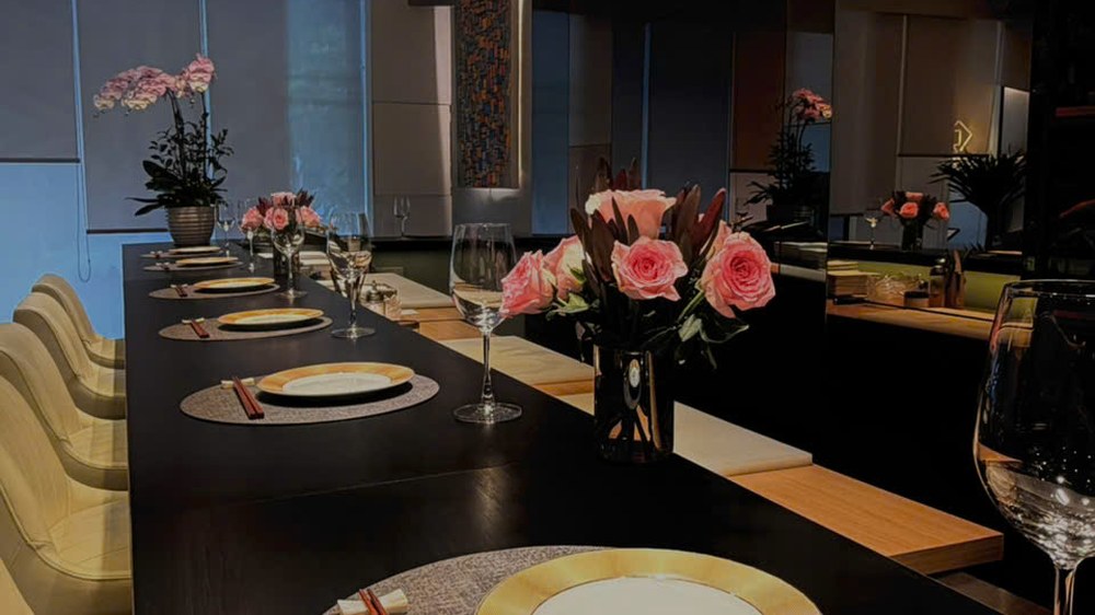 Kasen's long black-stone counter with gold-rimmed plates and cream leather chairs