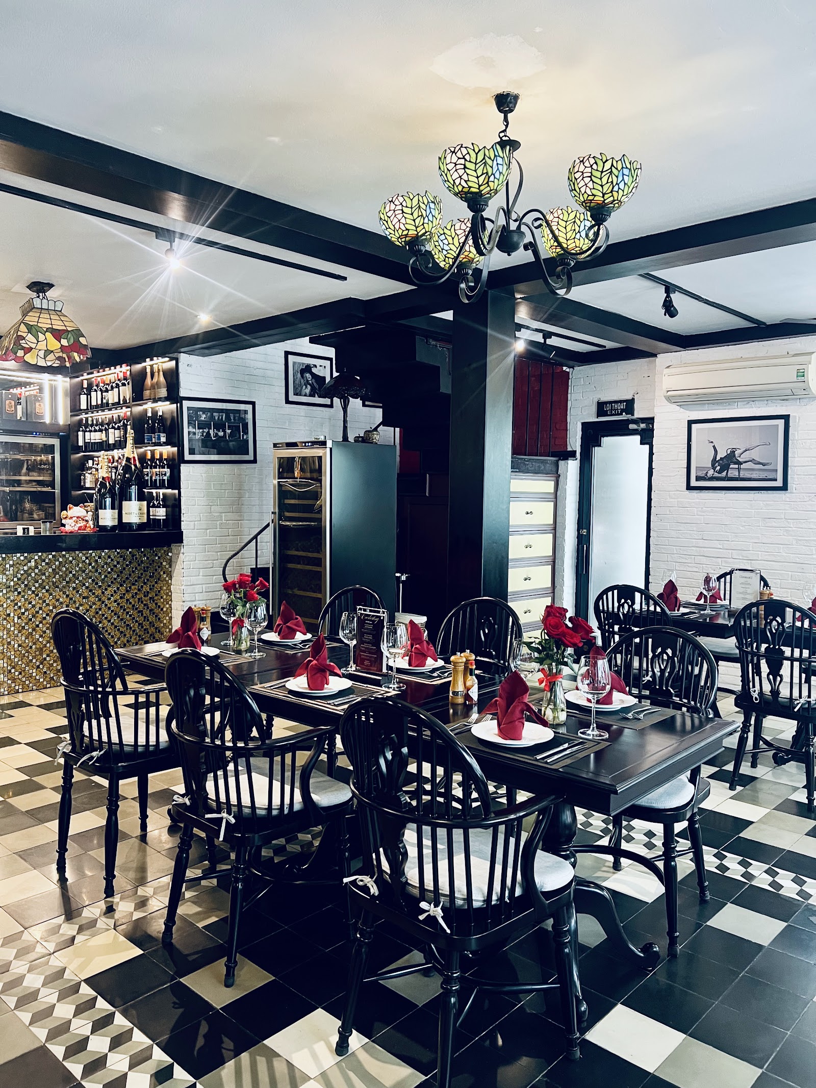 Đèn chùm kính màu Tiffany treo trên quầy rượu gỗ với kệ chai rượu