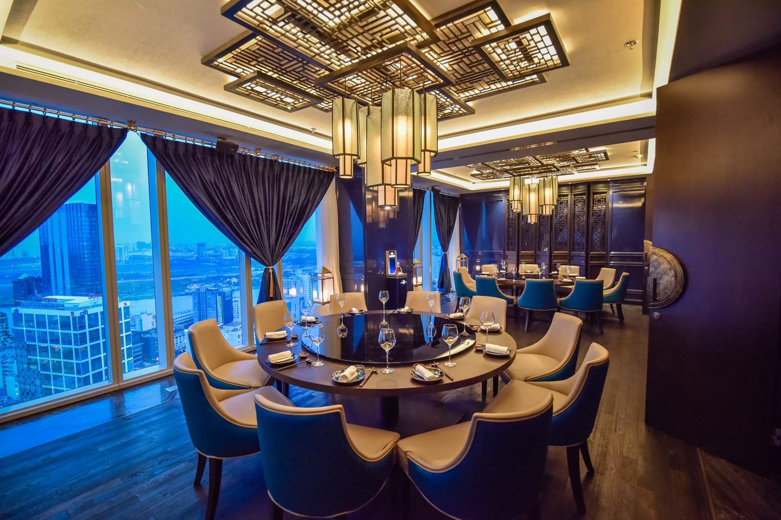 The Lai dining room — lazy-susan round tables, brass lattice lanterns, cream-and-blue chairs
