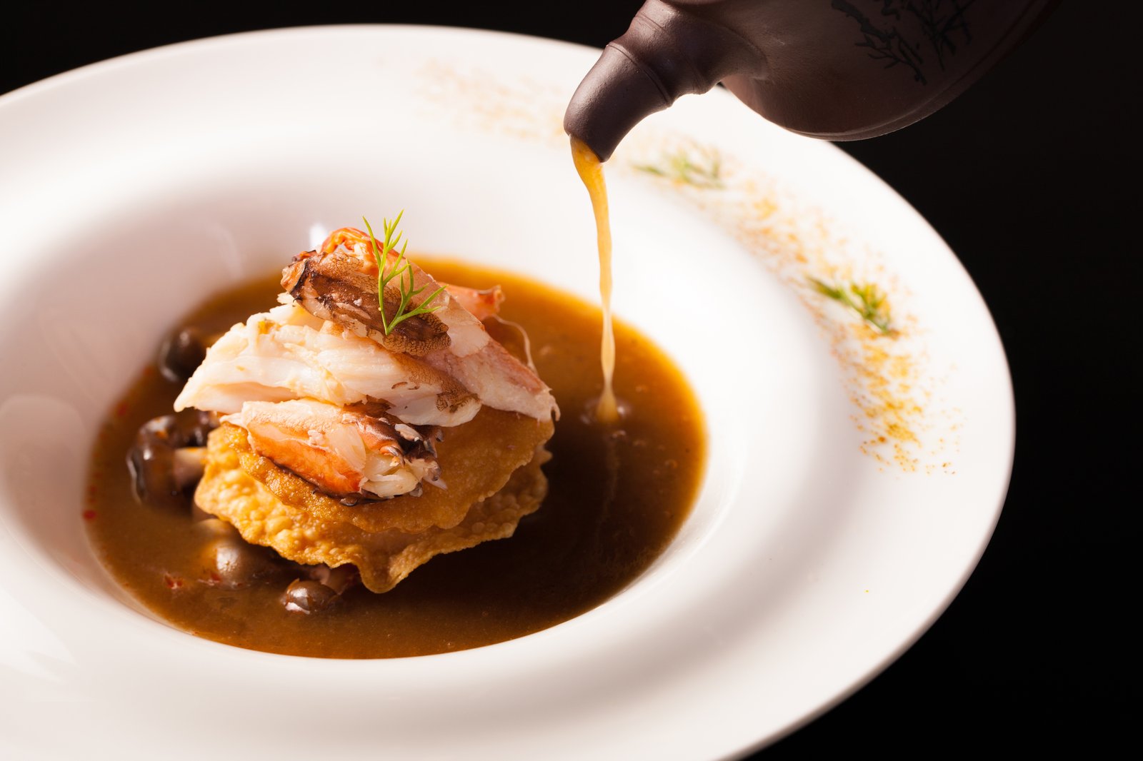 Seafood consommé poured at the table