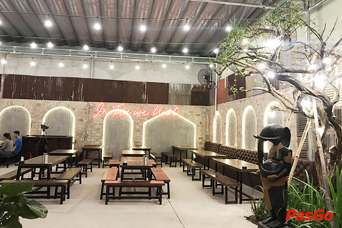 The beer hall: long communal tables, brick arches, the “In Tru we trust” neon