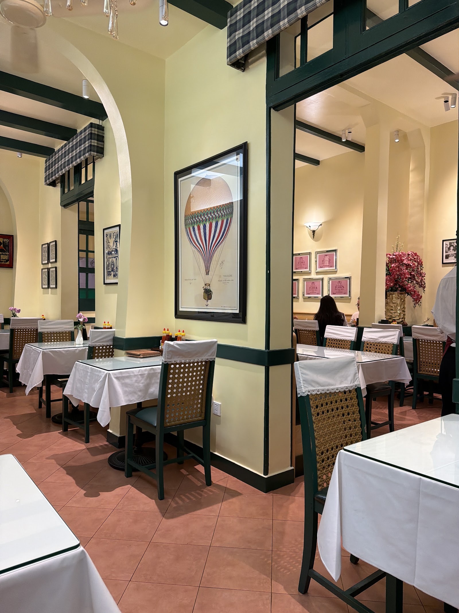 L'Etoile's dining room — white tablecloths, cane chairs, colonial green trim, the hot-air-balloon poster and framed certificates on the wall
