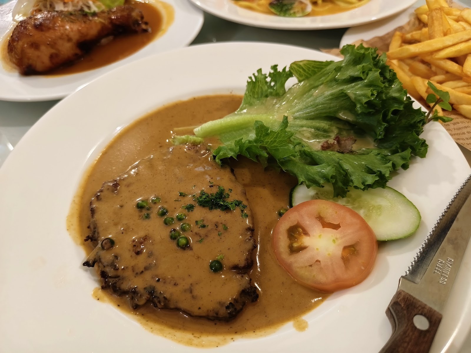 Pepper steak in green-peppercorn sauce with lettuce, tomato, cucumber and fries