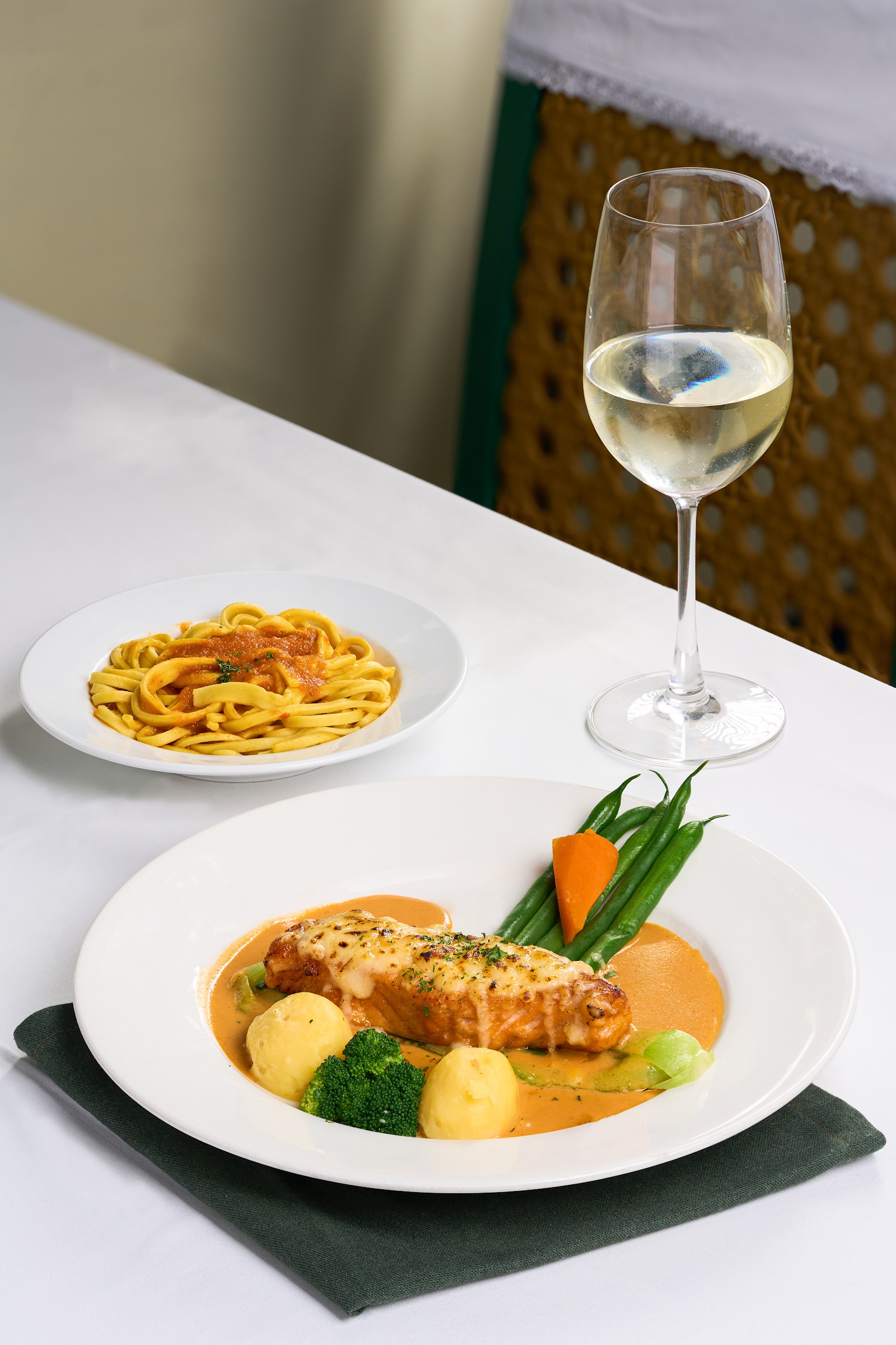 Salmon fillet with gratin, vegetables, pasta and a glass of white wine