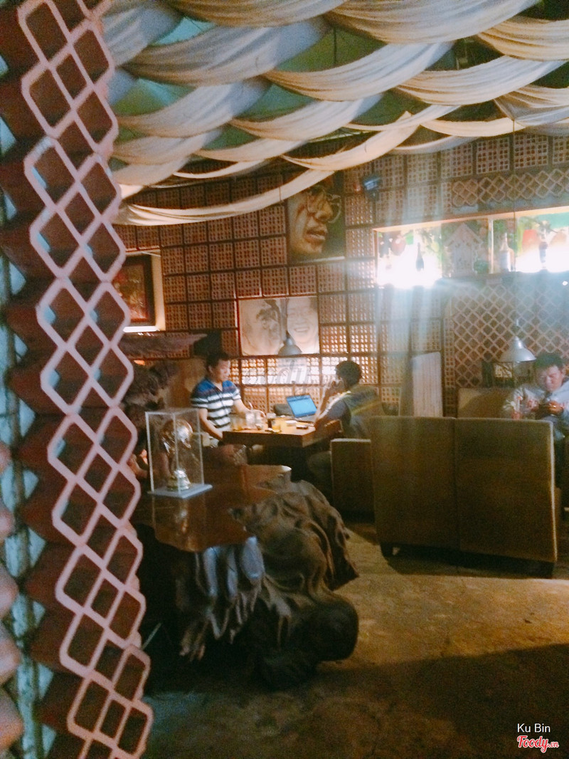 The working corner: red brick column, fabric ceiling, a guest on a laptop