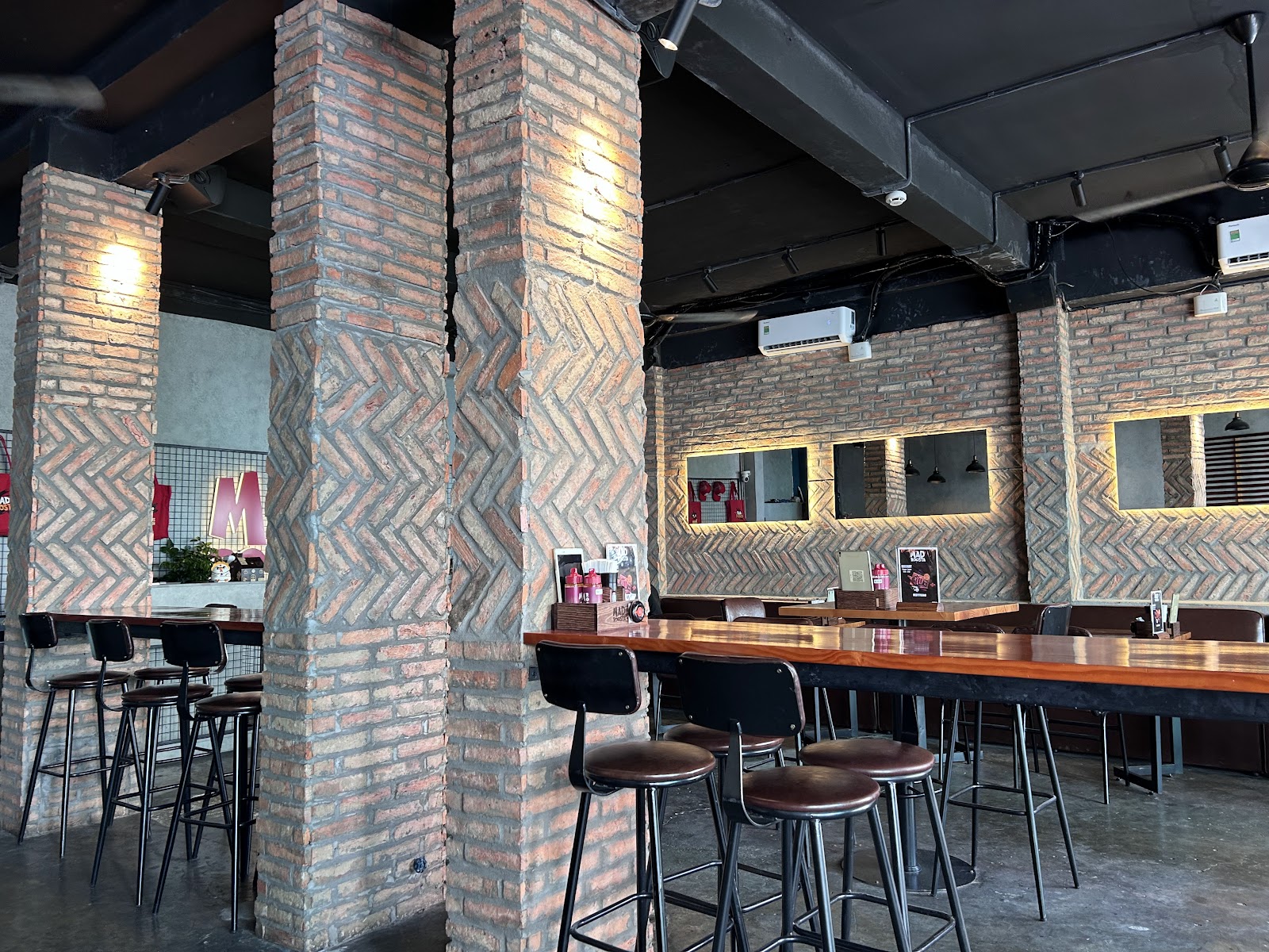 Không gian MAD ROOSTA — cột gạch và bàn bar cao