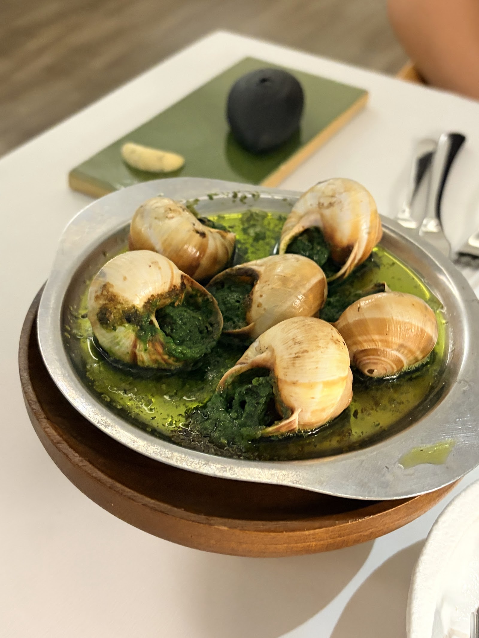Escargots in green herb butter in a metal pan — shells on