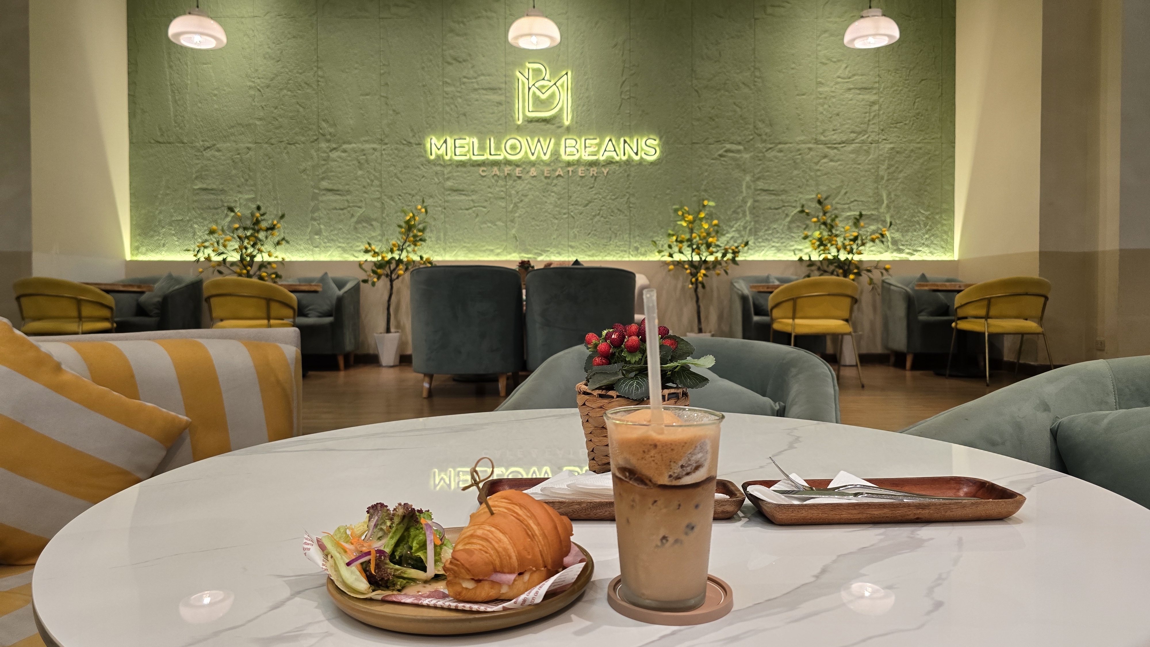 Croissant và cà phê đá bên tường logo