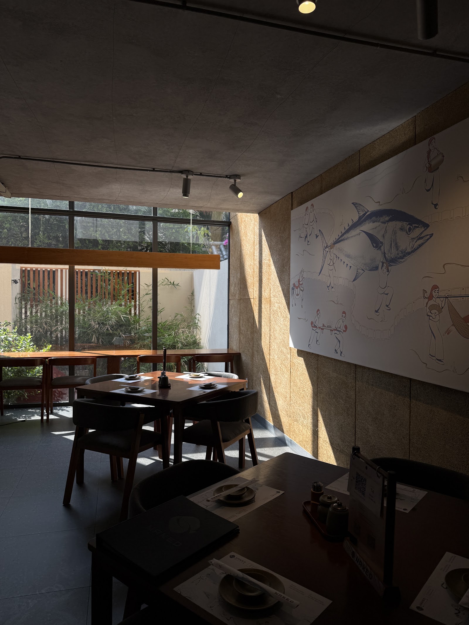 The dining room with the indigo tuna mural, dark wood tables, garden-facing windows