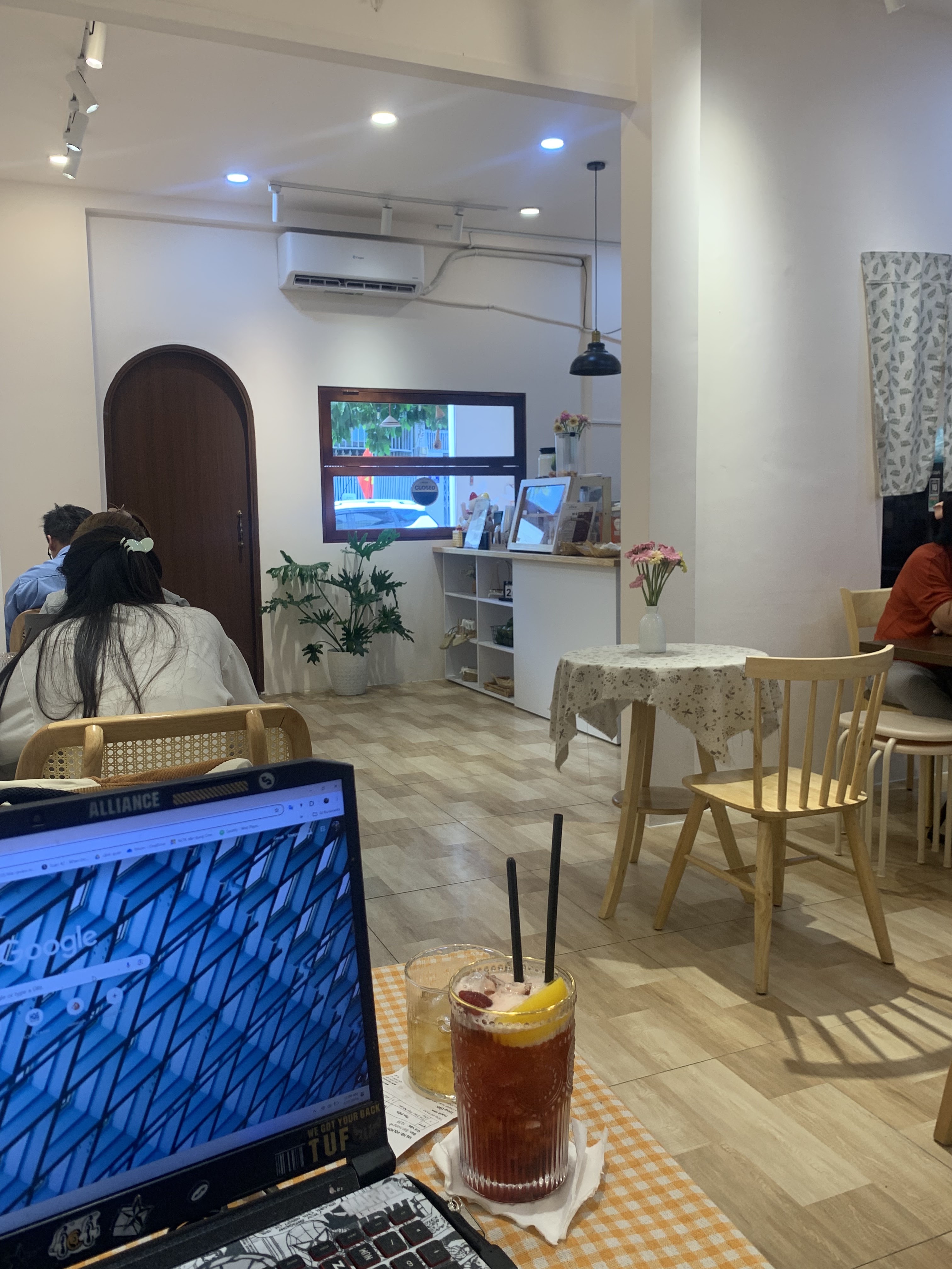 Không gian trong quán Nắng: bàn ghế gỗ, khách ngồi làm việc với laptop