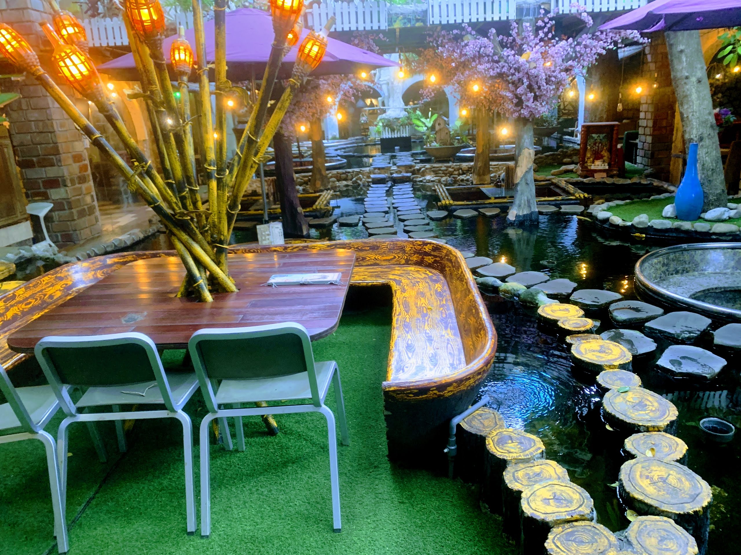 Hồ cá koi Oasis buổi tối với đuốc tre và bàn thuyền gỗ