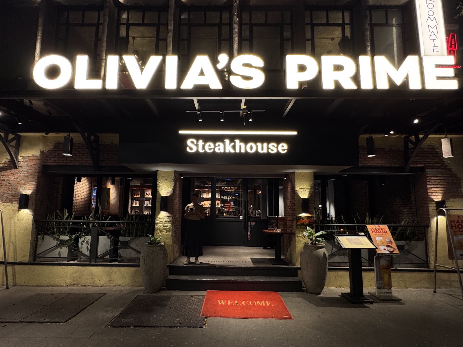 Mặt tiền Olivia's Prime Steakhouse về đêm, biển hiệu OLIVIA'S PRIME sáng đèn