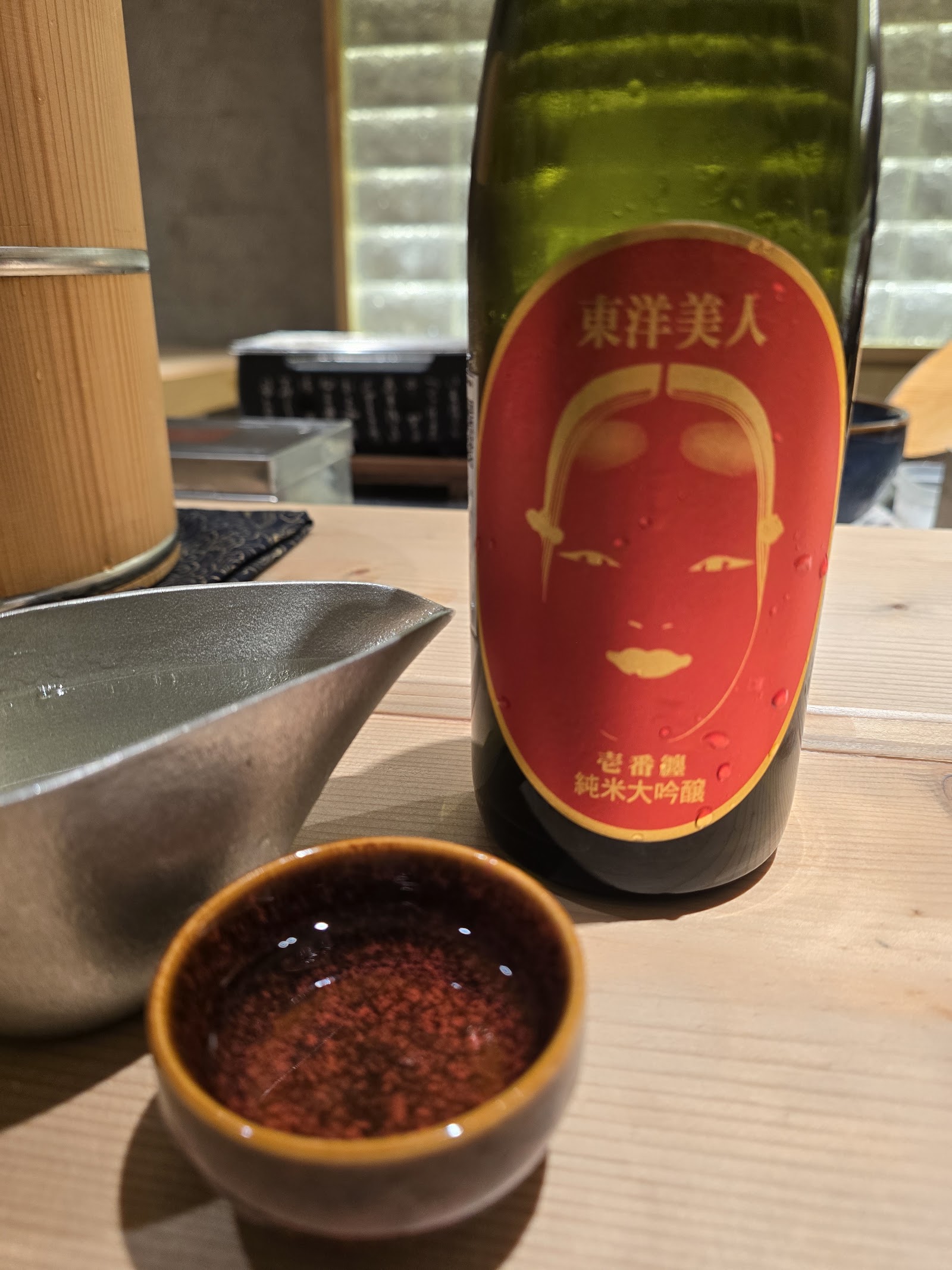 Tōyō Bijin junmai daiginjō on the counter — tin carafe, small cup, candlelight