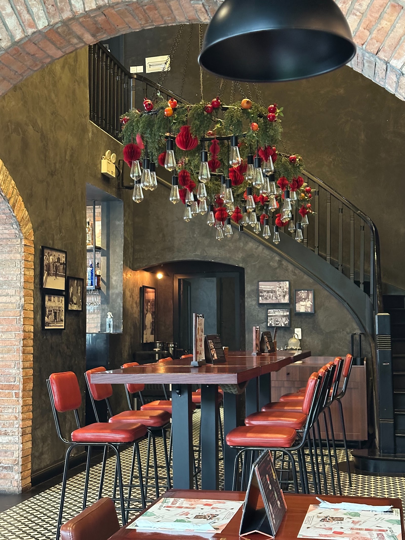 The bar corner with red leather stools under the filament chandelier