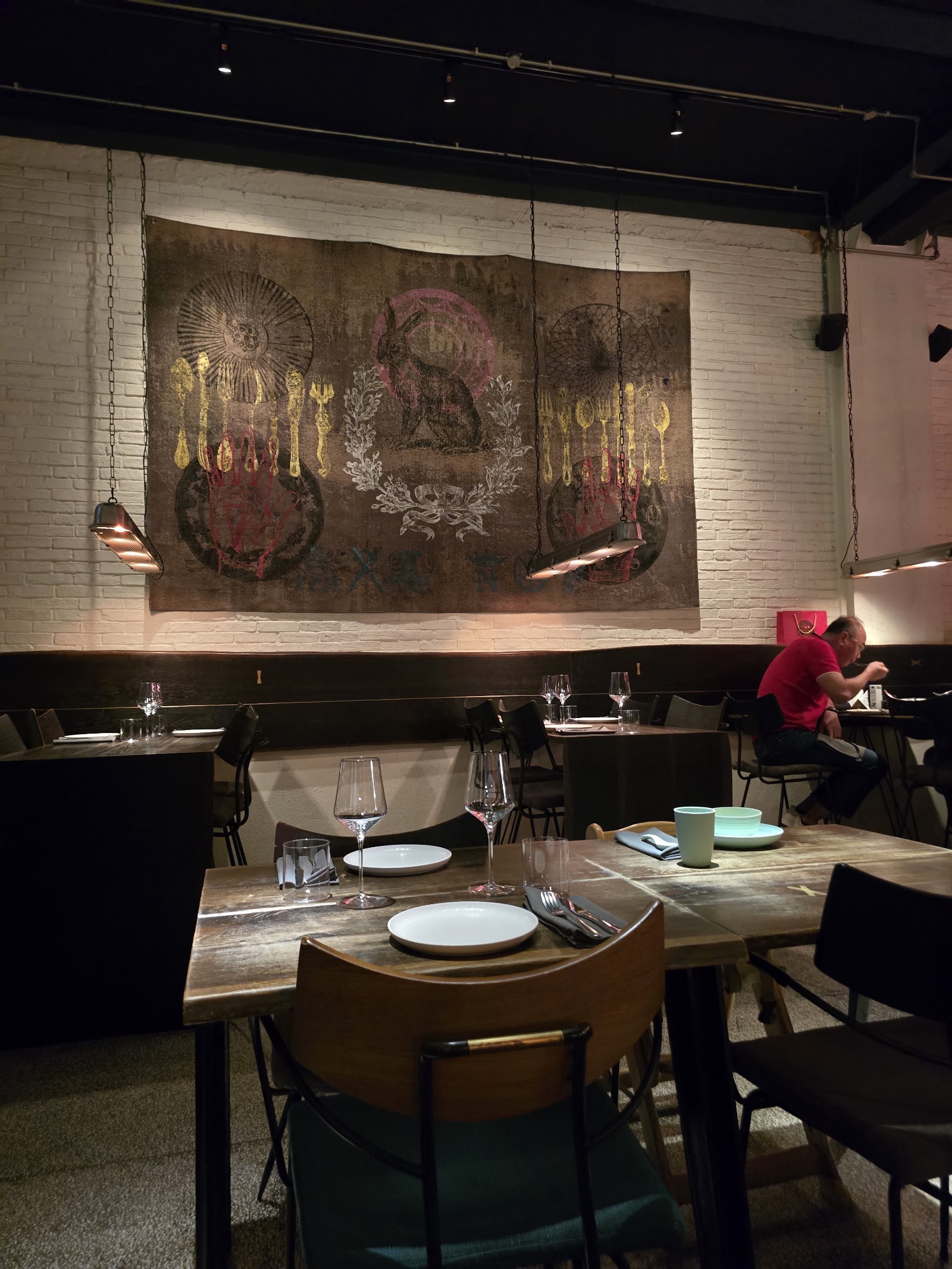 The dining room: dark timber, the mural wall, warm low light