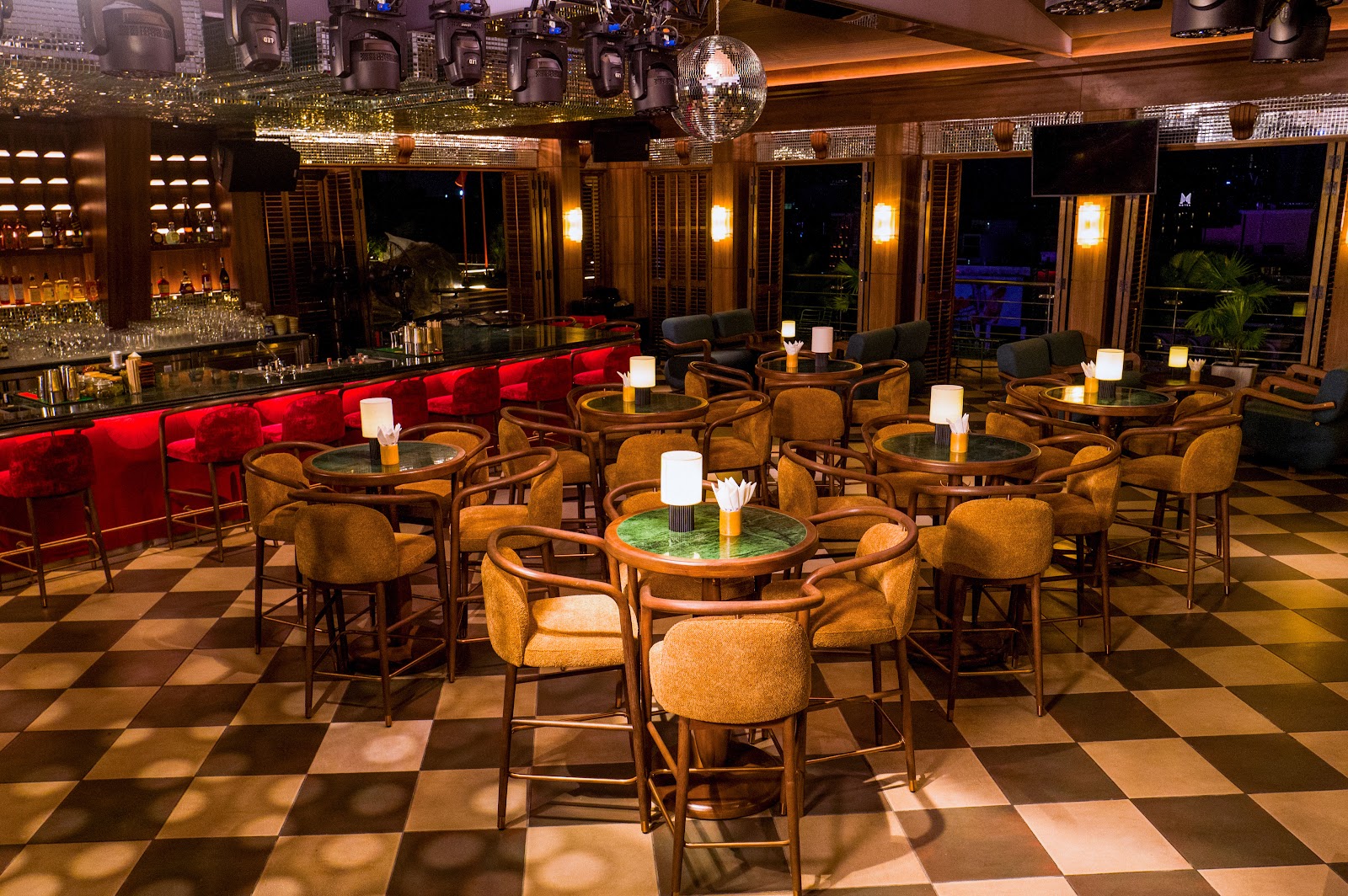 The indoor bar with brass lamps and red velvet chairs