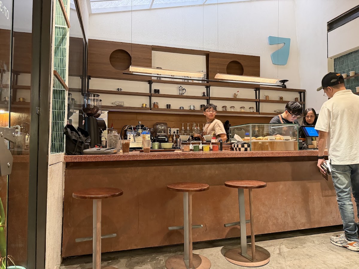 Sancara Caffe — quầy bar đồng, tủ bánh và barista