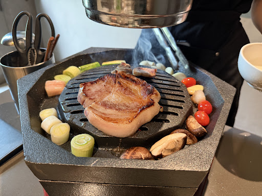 A thick pork steak sizzling on the octagonal cast-iron grill