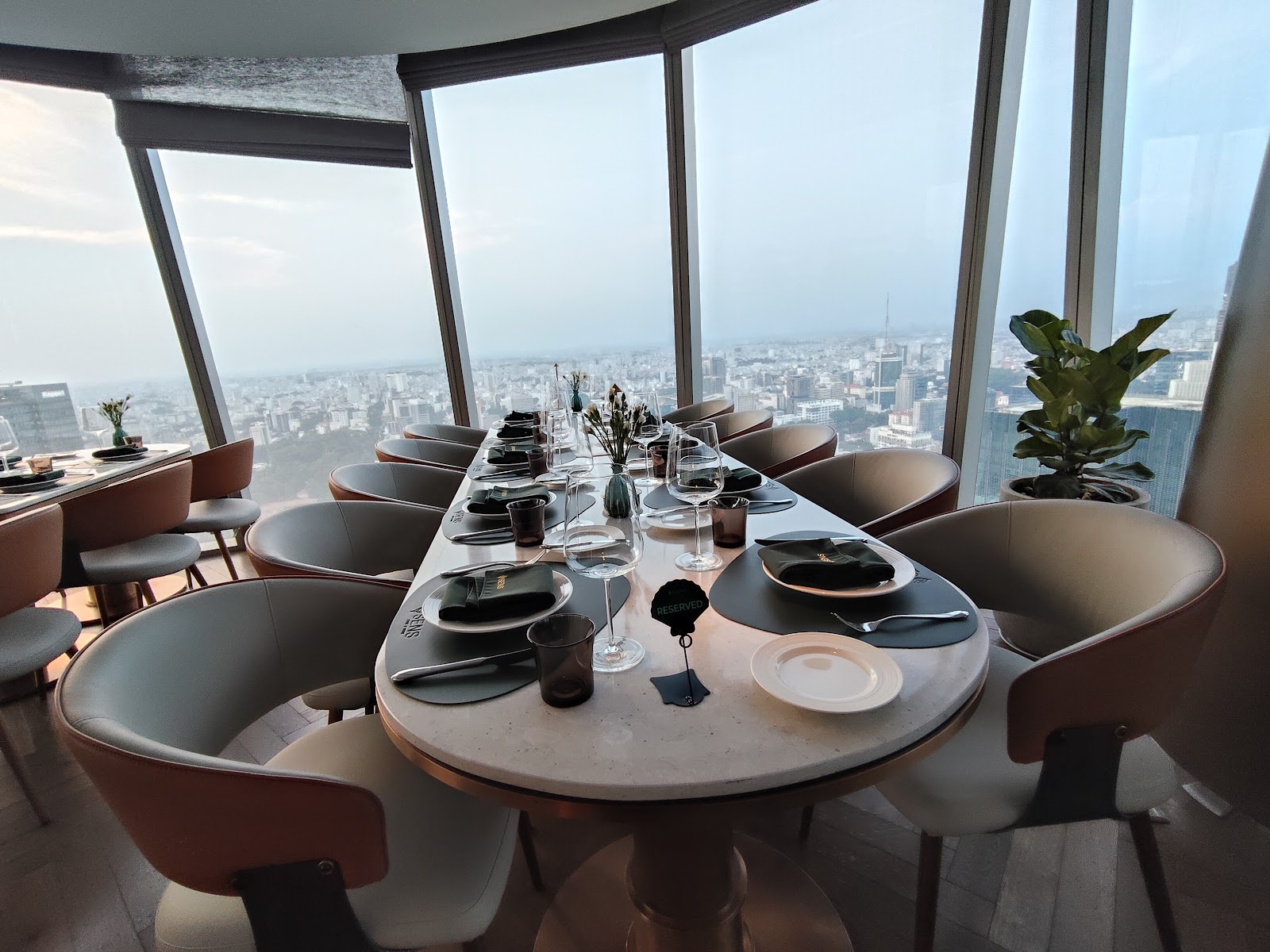 The dining room in daylight, the city beyond floor-to-ceiling glass