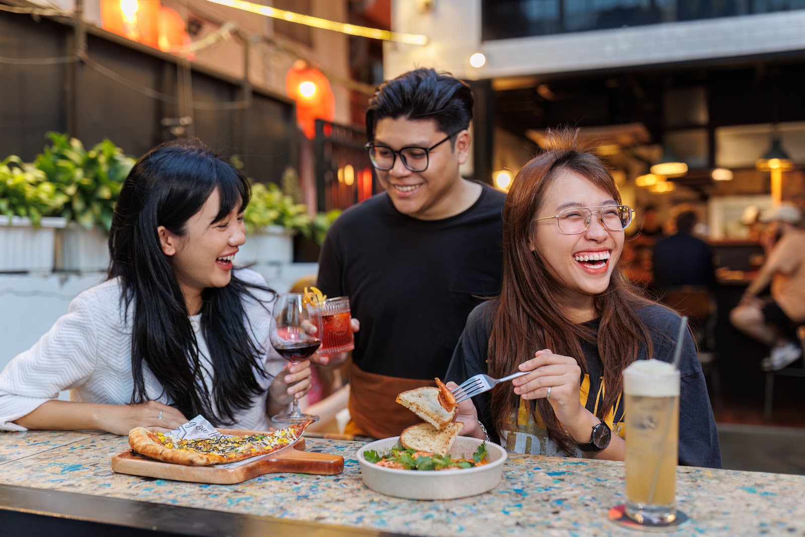 Nhóm bạn ăn uống ngoài trời cùng pizza và bia