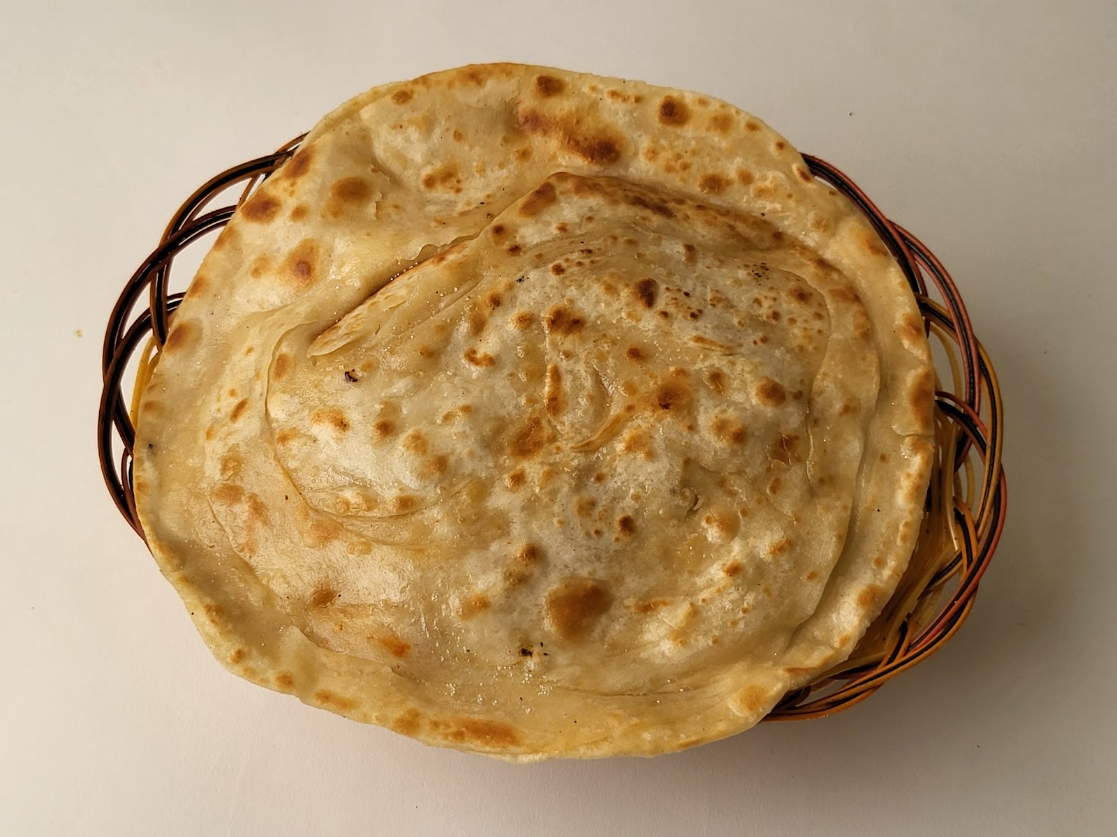 Flaky layered paratha in a wire basket