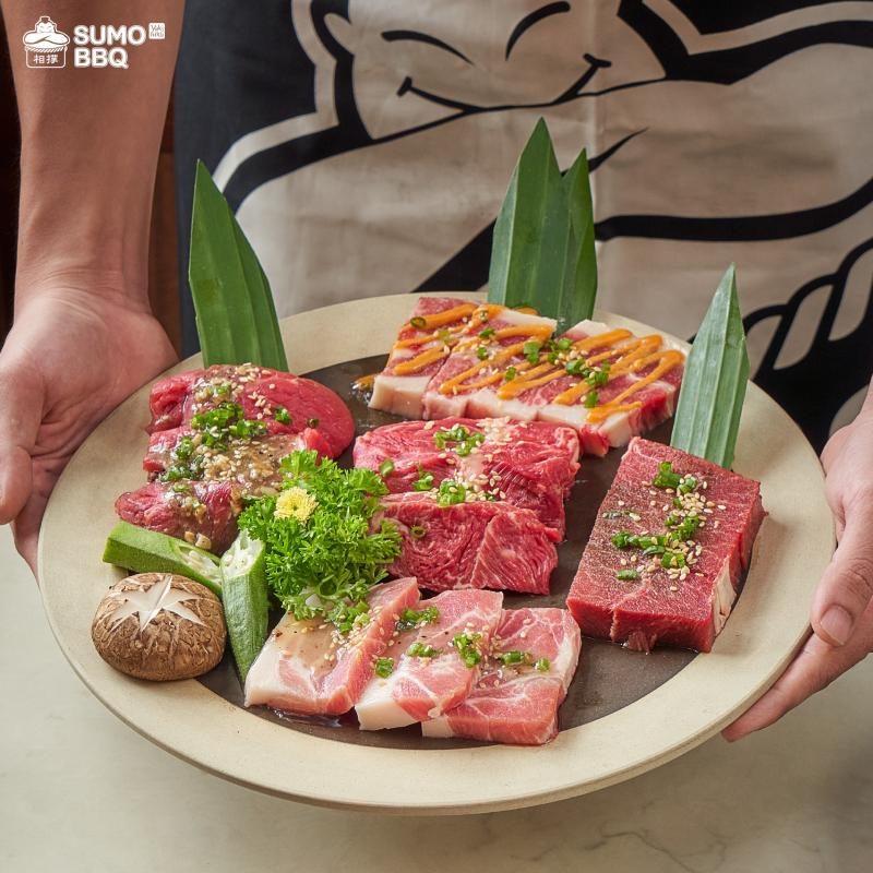 Staff member with a meat platter and sumo apron