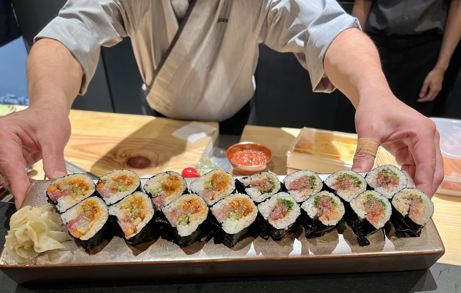 The chef presenting a maki platter across the counter