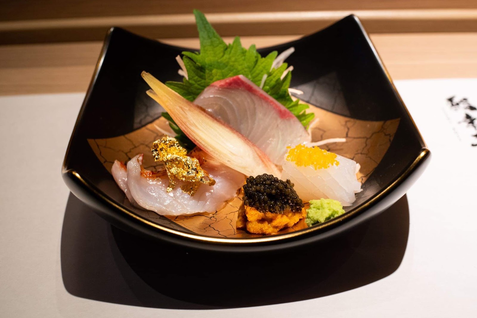 Sashimi phủ lá vàng, uni và caviar trên đĩa sơn mài đen