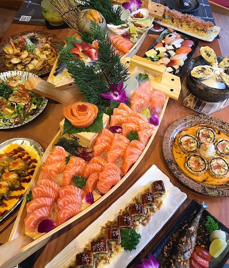 Thuyền gỗ chất đầy sashimi cá hồi, hoa hồng cá hồi và các món trên bàn