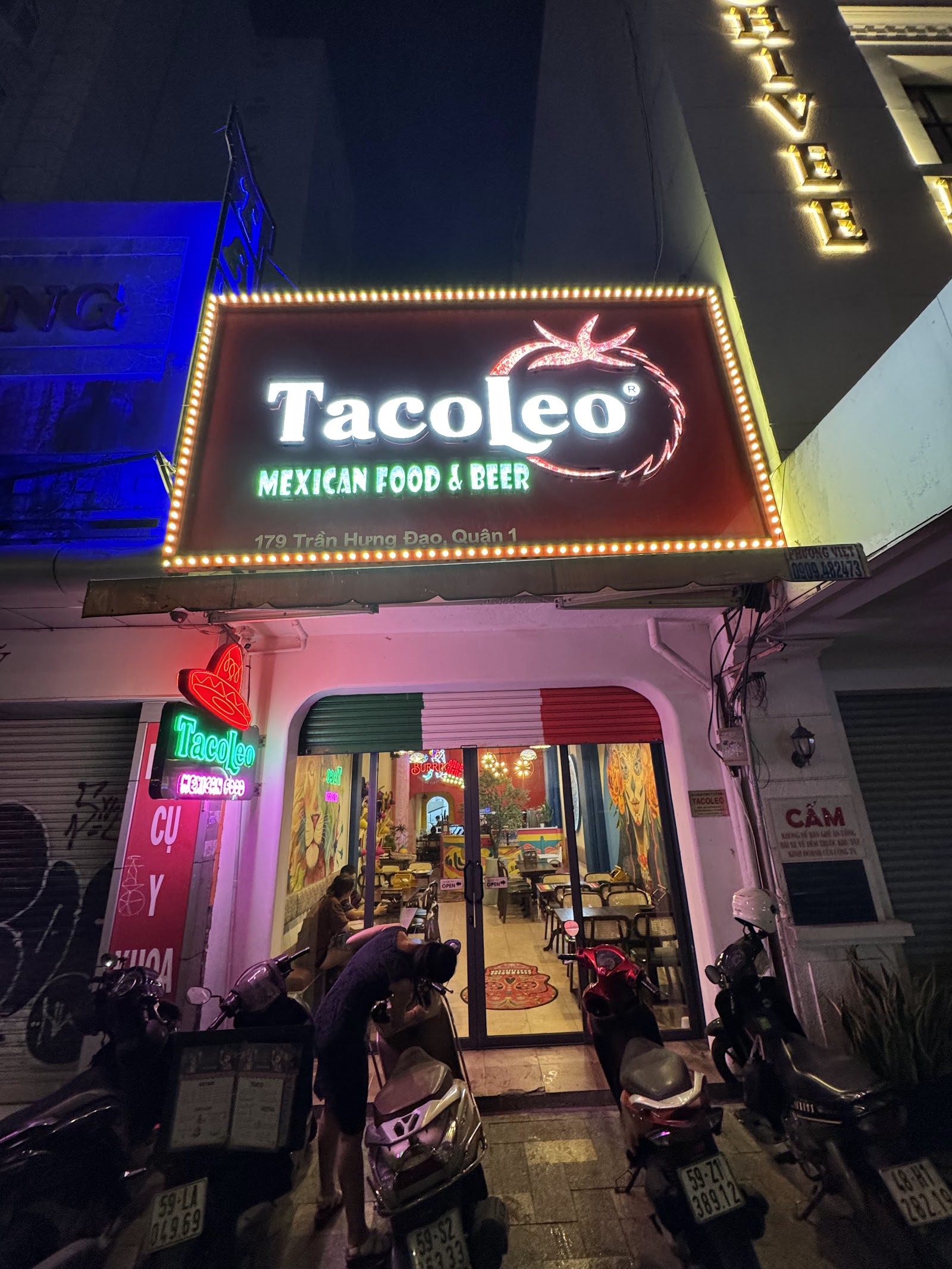 The TacoLeo storefront at night — the illuminated sign, 179 Trần Hưng Đạo
