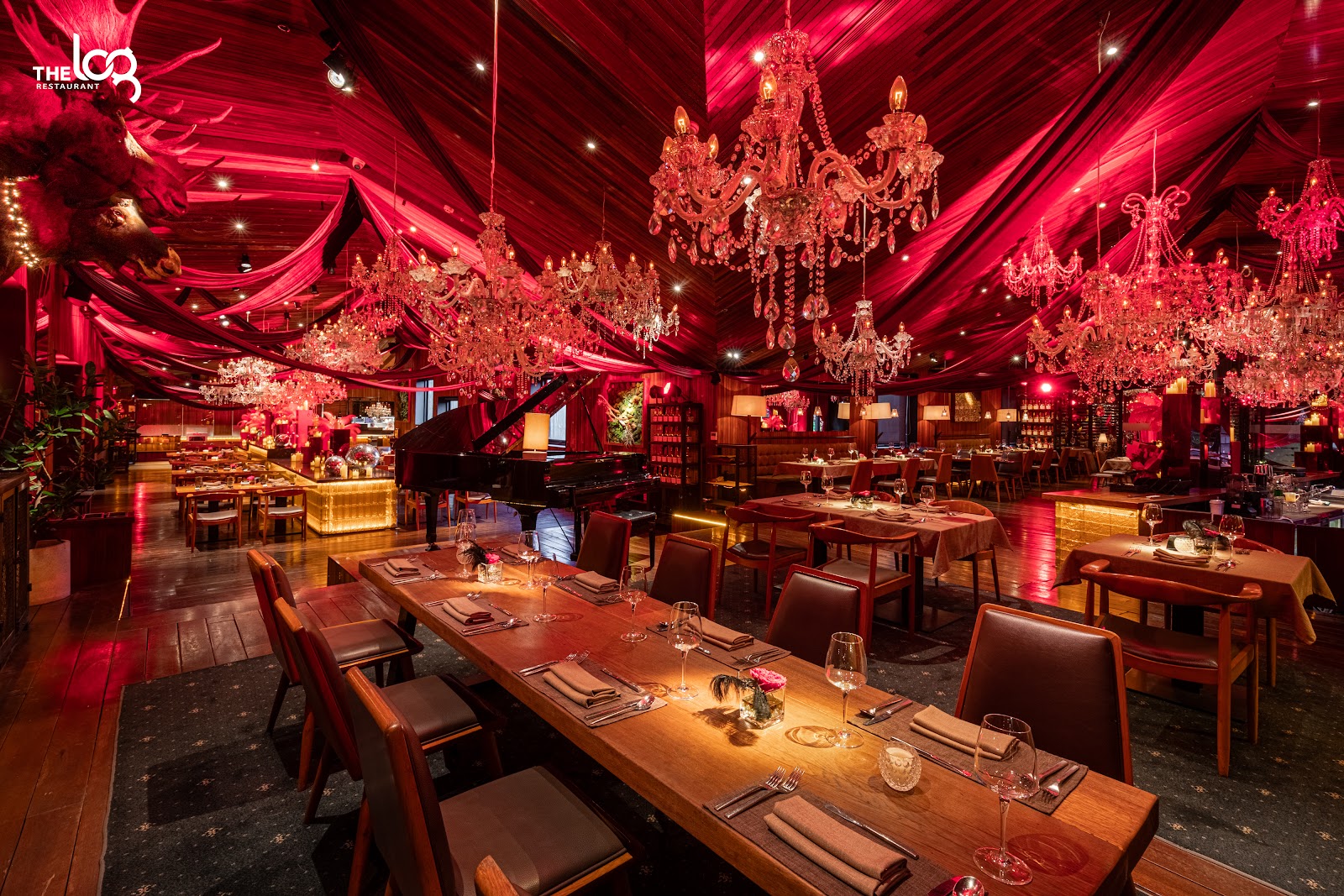 The red-draped dining hall — chandeliers, long tables and a grand piano